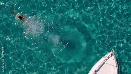 Aerial - Top view of a beautiful young woman jumping from a motor boat bow