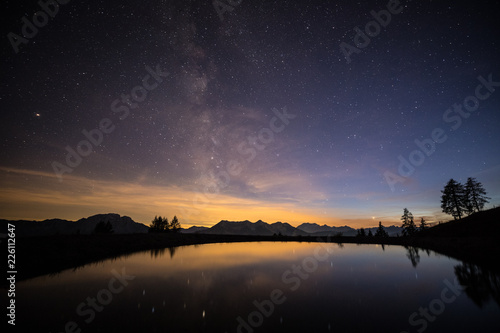 Milkyway Nightsky With Lake Mountains & Trees At Emberger Alm In The Austrian Alps