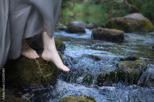 barefoot women's feet on a stone among the fast-flowing river