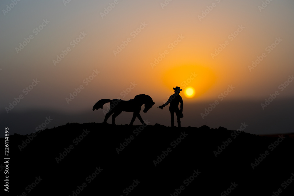 Cowboy concept. Silhouette of Cowboys at sunset time. A cowboy silhouette on a mountain with an yellow sky.