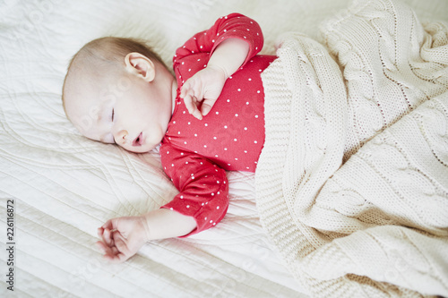 Baby girl sleeping under knitted blanket