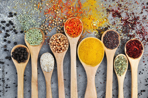 Colorful mix of herb and spice varieties: curry, coriander, turmeric, cumin, paprika, pepper, mustard, salt, thyme, cardamon, oregano, saffron, cinnamon; food ingridients background