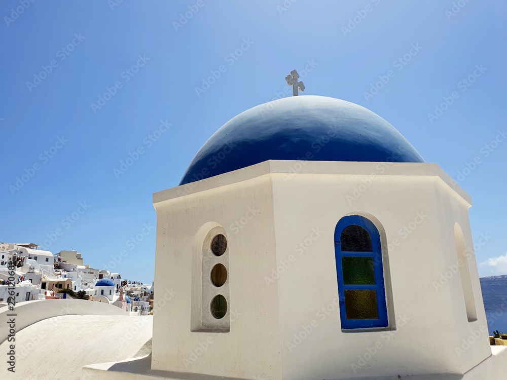 Traditional blue dome church in the beautiful city or Oia, Santorini against blue sky