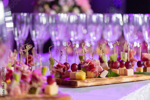 the buffet at the reception. Glasses of wine and champagne. Assortment of canapes on wooden board. Banquet service. catering food  snacks with cheese  jamon  prosciutto and fruit