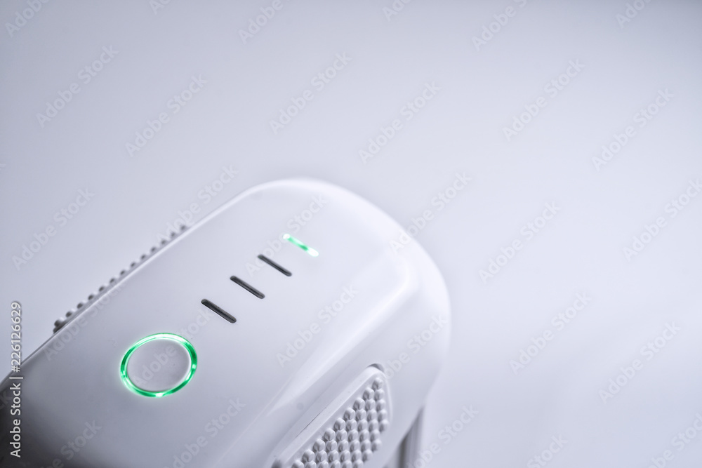 A white drone smart Battery pack with LED indicator lights ON, on white isolated background A white drone smart Battery pack with LED indicator lights ON, on white isolated background