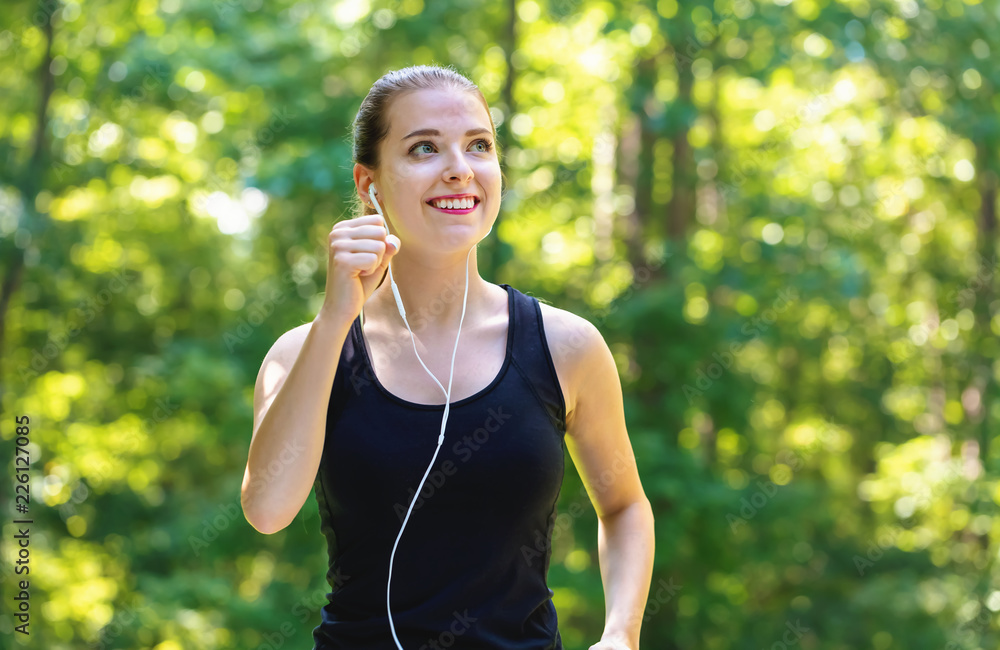 Athletic young woman jogging on a bright summer day in the forest Athletic young woman jogging on a bright summer day in the forest
