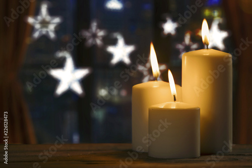 Burning candles with blurred Christmas lights