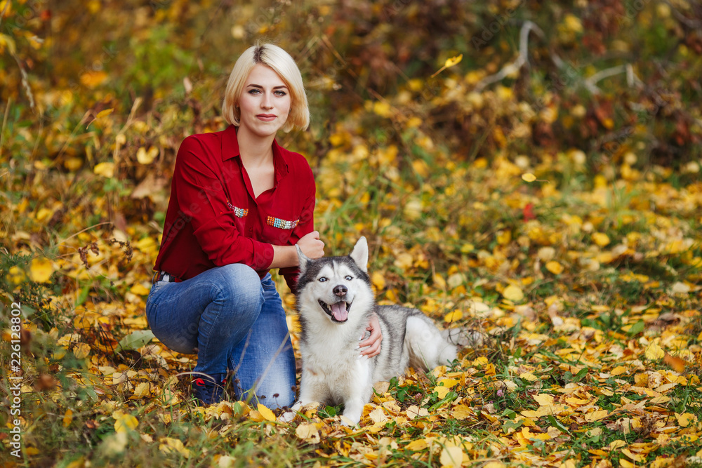 Beautiful caucasian girl plays with husky dog in autumn forest Beautiful caucasian girl plays with husky dog in autumn forest