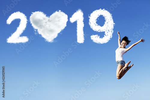 Cheerful woman jumps with number 2019