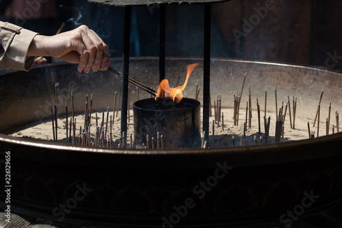 Close-up of a hand burning an incense stick at a temple in Japan