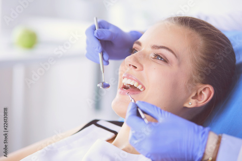 Young Female patient with open mouth examining dental inspection at dentist office. photo