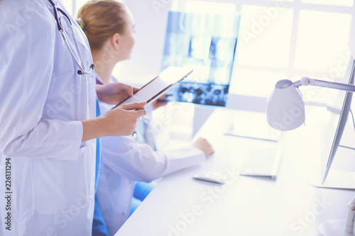 Close up shoot of doctor with tablet and colleague with x-ray on the background.