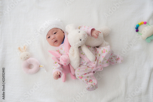 4 weeks old newborn baby in pink laying down with stuffed animal toys