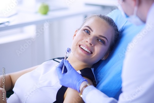 Young Female patient with pretty smile examining dental inspection at dentist office.