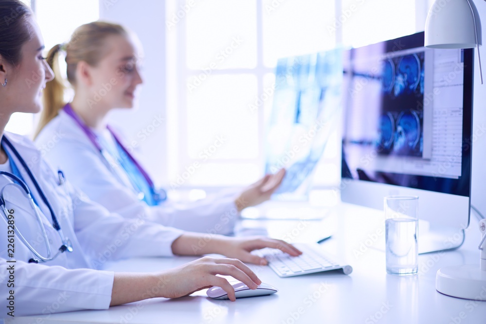 Two young female doctors working on computer at hospital. Two young female doctors working on computer at hospital.