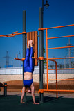 Girl on the street workout. She wears blue sports clothes upside down. Healthy lifestyle.