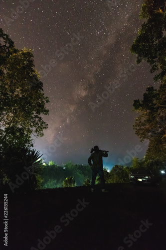 Silhouette of a cameraman will shooting a milky way