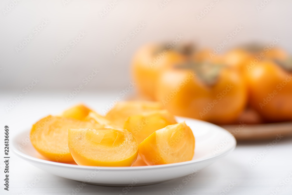 Sliced persimmon fruit on white dish for eating, healthy fruit