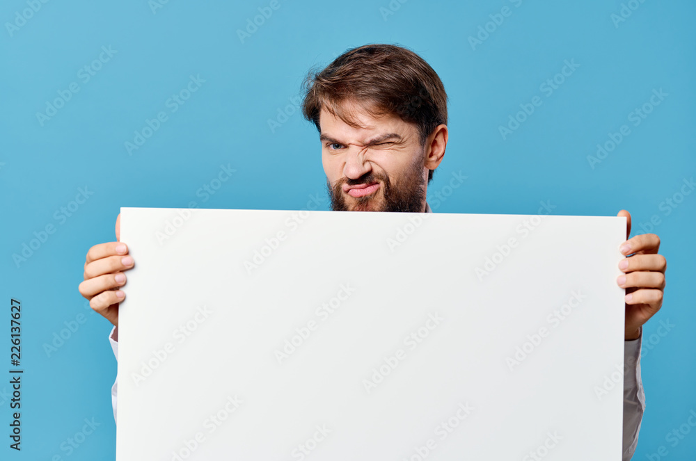 emotions man with a beard holding a white sheet of paper place free on a blue background emotions man with a beard holding a white sheet of paper place free on a blue background