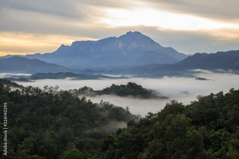 Beautiful sunrise landscape scenery with sunlight and fog and Mount Kinabalu as background in Guakon, Sabah, Malaysia Beautiful sunrise landscape scenery with sunlight and fog and Mount Kinabalu as background in Guakon, Sabah, Malaysia