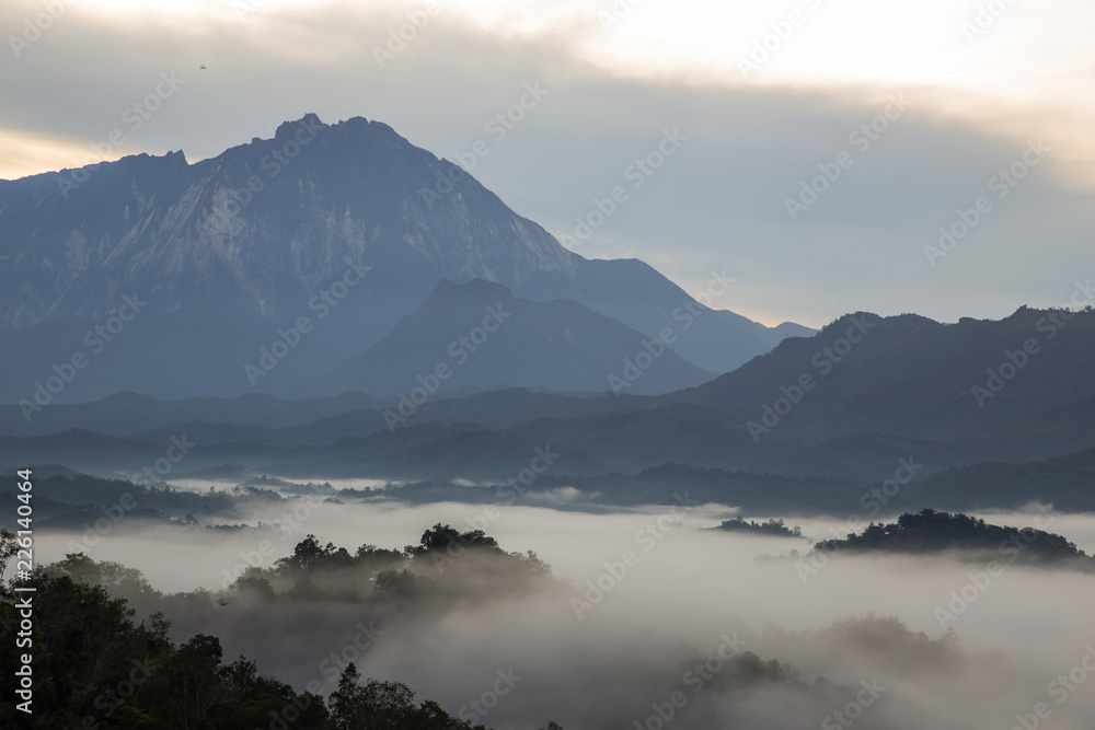 Beautiful sunrise landscape scenery with sunlight and fog and Mount Kinabalu as background in Guakon, Sabah, Malaysia