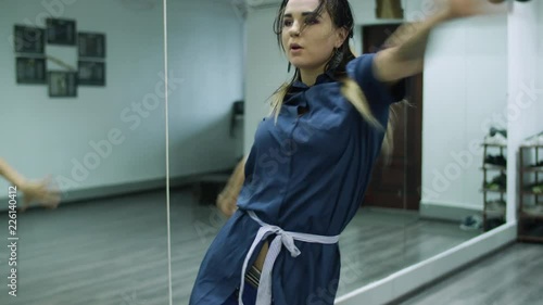 Slow motion shot of caucasian female dancer choreographer performing contemporary dance routine against a mirror wall in a dance studio photo