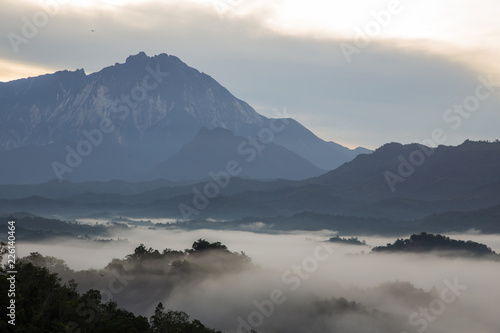 Beautiful sunrise landscape scenery with sunlight and fog and Mount Kinabalu as background in Guakon, Sabah, Malaysia