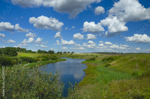 Sunny summer landscape with river,fields,green hills and beautiful clouds in blue sky.River Upa in Tula region,Russia. 