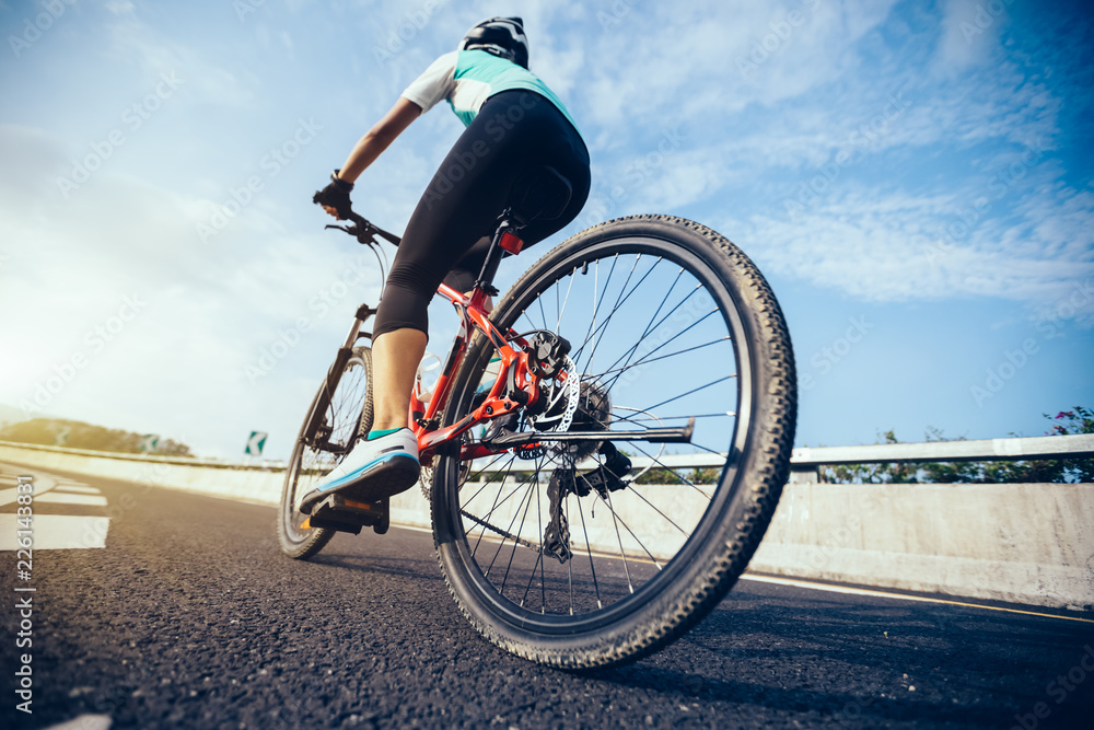 Woman cyclist riding Mountain Bike on highway Woman cyclist riding Mountain Bike on highway