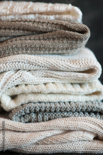 A stack of textured knitted things of light colors. The concept of comfort, warmth.