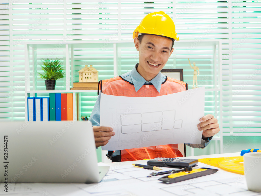 Young Asian man architect working at working desk about his housing project. Young Asian man architect working at working desk about his housing project.