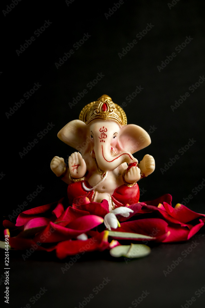 Lord Ganesha Idol with rose petals, white flowers and leaves on Black