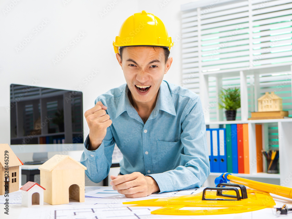 Young Asian man architect working at working desk about his housing project. Young Asian man architect working at working desk about his housing project.