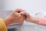People holding hands together indoors. Help and elderly care service