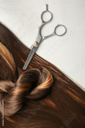 Flat lay composition with brown hair and scissors on gray background