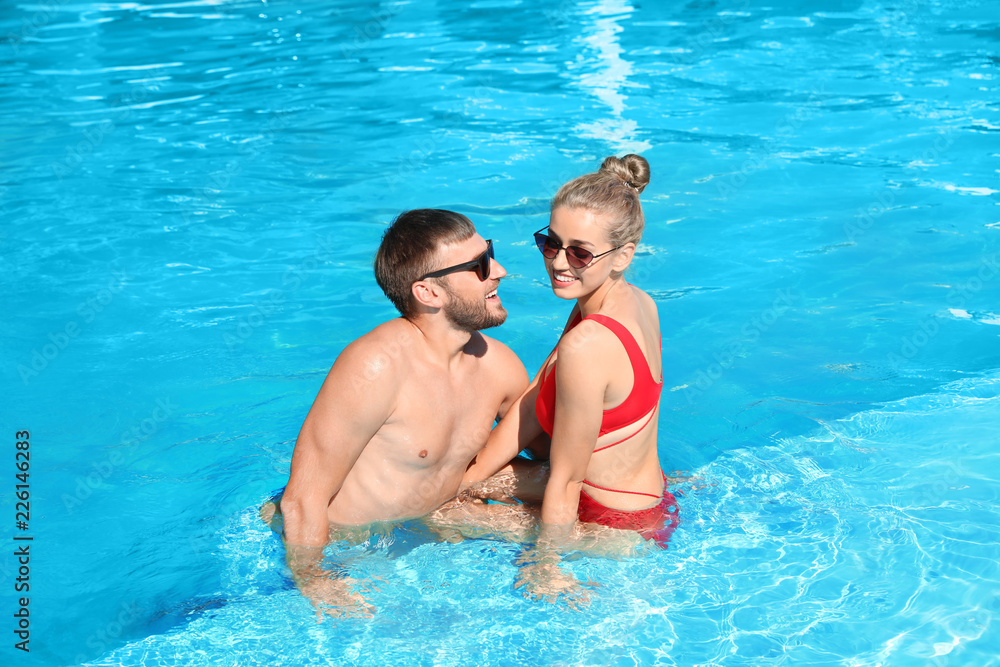 Happy young couple relaxing in swimming pool at resort