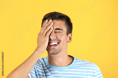 Portrait of handsome young man laughing on color background