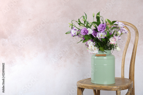Vase with bouquet of beautiful flowers on chair against color background. Space for text