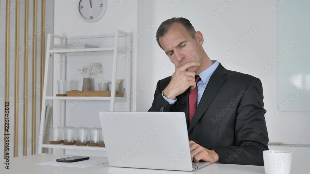 Pensive Middle Aged Businessman Thinking and Working on Laptop Pensive Middle Aged Businessman Thinking and Working on Laptop
