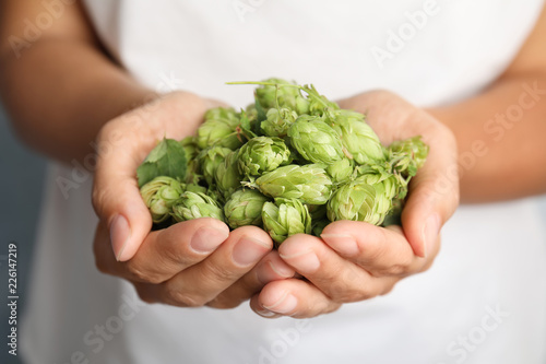 Woman holding fresh green hops, closeup. Beer production