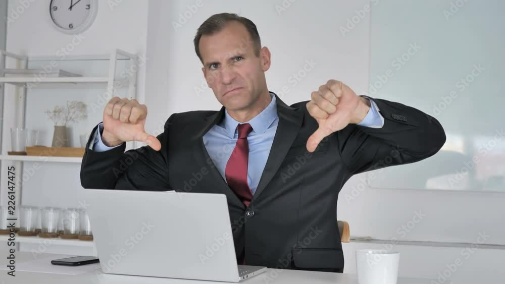 Thumbs Down by Middle Aged Businessman Looking at Camera Thumbs Down by Middle Aged Businessman Looking at Camera