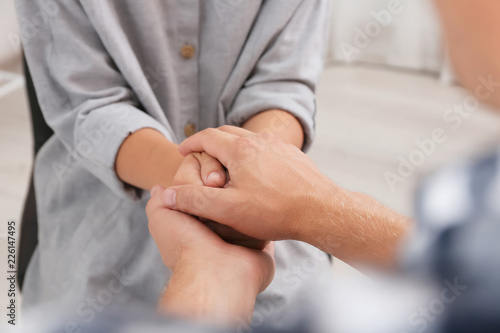 Man holding woman's hands indoors, closeup. Concept of support and help