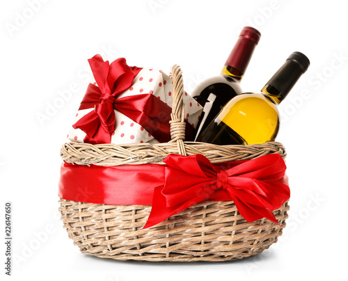Festive basket with bottles of wine and gift on white background