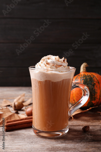 Glass cup with tasty pumpkin spice latte on wooden table