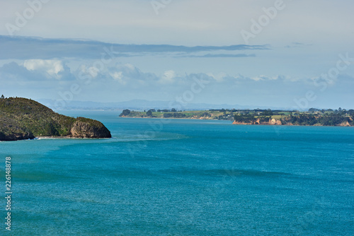 View of blue waters across a bay under a bright blue sky with some clouds
