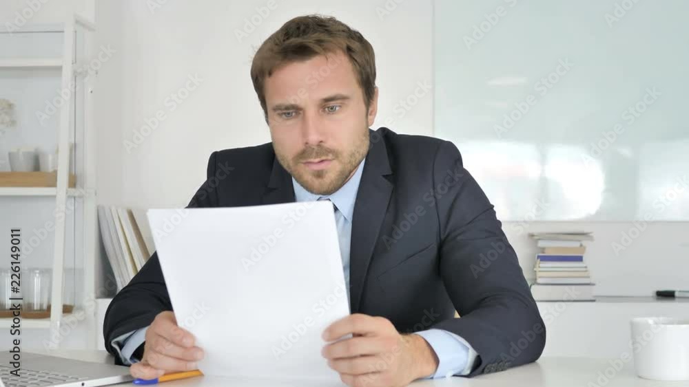Businessman Reacting to Loss while Reading Documents Businessman Reacting to Loss while Reading Documents