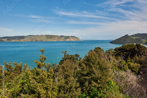 View of blue waters across a bay under a bright blue sky with some clouds