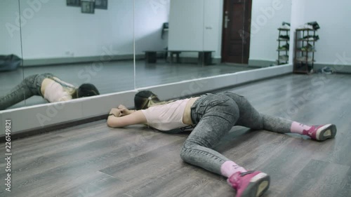 Caucasian female dancer choreographer stretches and warms up on the floor of a dance studio photo
