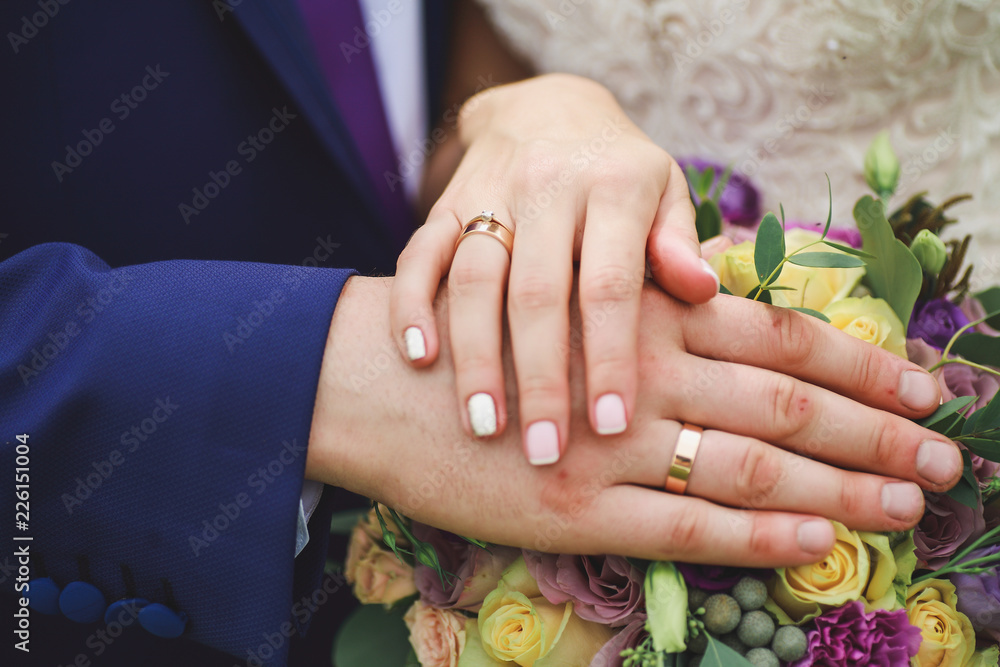 hands of the newlyweds on the wedding bouquet