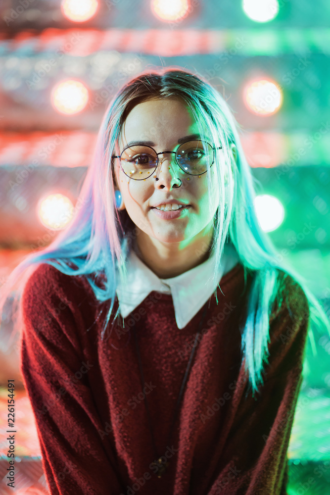 Hipster girl with blue dyed hair and sequins as freckles. Woman in red  clothing and nose piercing, transparent glasses, ears tunnels, unusual  hairstyle in amusement park Stock Photo | Adobe Stock